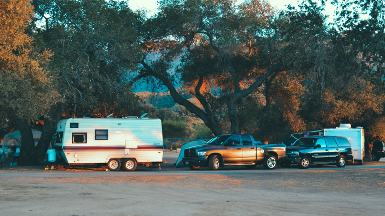 Das Bild zeigt einen Camper und zwei Autos 